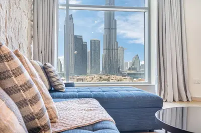 a living room with a blue couch and a large window at Premium Home with Panoramic Burj Khalifa Views in Dubai