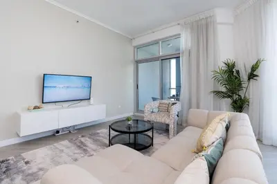 a white living room with a couch and a tv at Stunning Interior in an deal Location in Dubai
