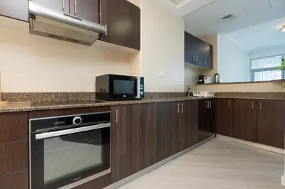 a kitchen with wooden cabinets and a microwave at Stunning Interior in an deal Location in Dubai