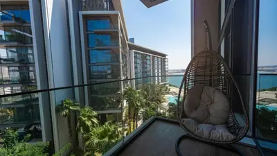 a hanging chair on a balcony with a view of the ocean at Bluewaters Island - Luxury 2BR with Ain View by TLRE Holiday Homes in Dubai
