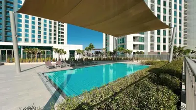 a swimming pool with a large umbrella in front of a building at 4BR with Spacious Balcony & Stunning Burj Khalifa Views in Dubai