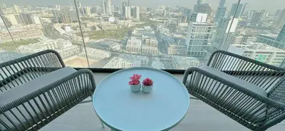 two chairs and a table with two flowers on it at Modern 1br In Jvc Balcony, Pool & Free Parking in Dubai