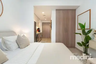 a bedroom with a white bed and a bathroom at 12min from Burj Khalifa - Studio - Azizi Riviera in Dubai