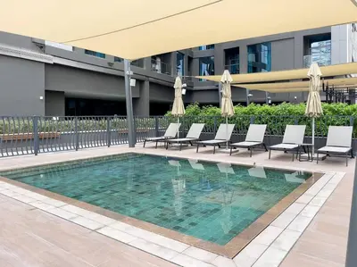 a swimming pool with chairs and umbrellas in a building at Rare Luxury 1bdr 15 Northside in Dubai