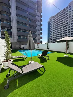 a patio with grass and an umbrella and a pool at Luxury Studio Apartment In Dubai Marina in Dubai