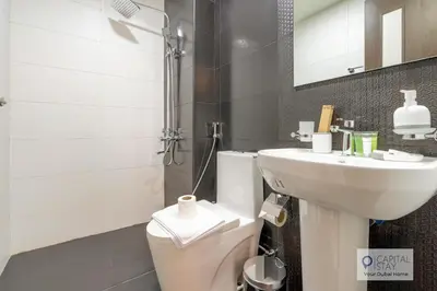 a white bathroom with a sink and a toilet at Capital Stay - Cozy Studio in Liwan Dubai in Dubai