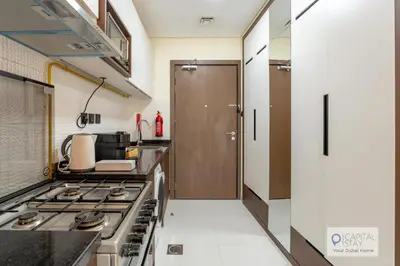 a kitchen with a stove top oven in a room at Capital Stay - Cozy Studio in Liwan Dubai in Dubai