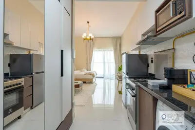 a kitchen with stainless steel appliances and a living room at Capital Stay - Cozy Studio in Liwan Dubai in Dubai