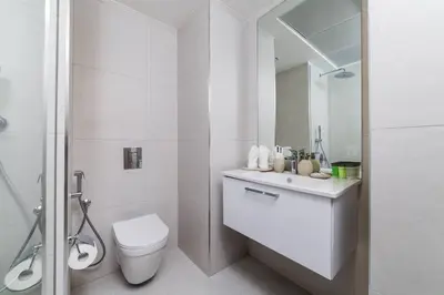 a white bathroom with a toilet and a sink at Waves - Luxury Meets Comfort, Modern 1BR in JVCs Luma22 in Dubai