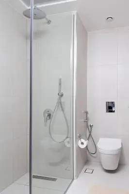 a white bathroom with a shower and a toilet at Waves - Luxury Meets Comfort, Modern 1BR in JVCs Luma22 in Dubai