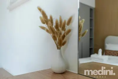 a white vase with flowers in it on a table at 1-Bedroom - in Emaar Creek Harboor in Dubai