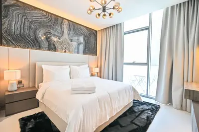 a bedroom with a large white bed and a window at Centrally Located 1 Bedroom in District One Meydan in Dubai