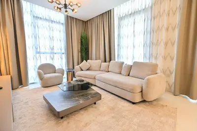 a living room with a couch and a table at Chic Retreat 1BR in District One Meydan in Dubai