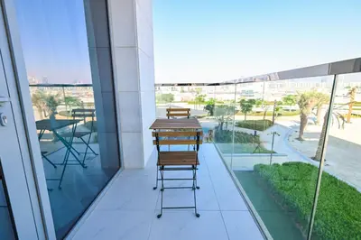 a balcony with chairs and tables on a building at Chic Retreat 1BR in District One Meydan in Dubai