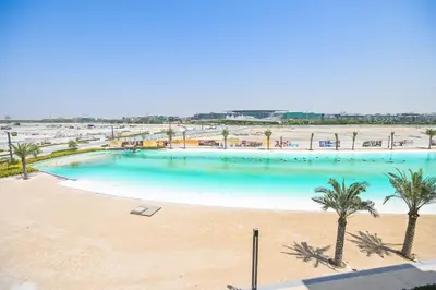an overhead view of a large swimming pool with palm trees at Family-friendly 1 Bedroom in District One Meydan in Dubai