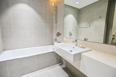 a bathroom with a white sink and a tub and a tubermottermott at Gorgeous 1 Bedroom in District One Meydan in Dubai