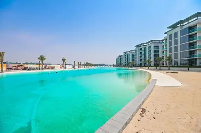 a large swimming pool next to a beach with buildings at Modern 1BR in District One Meydan in Dubai