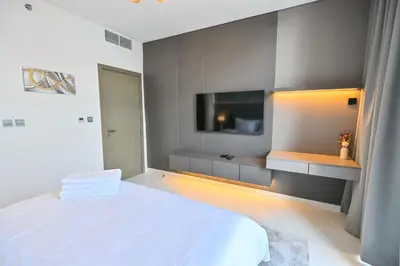 a bedroom with a white bed and a flat screen tv at 1BR w Exclusive Lagoon Access in District One Meydan in Dubai