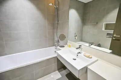 a bathroom with a white sink and a bath tub at 1BR w Exclusive Lagoon Access in District One Meydan in Dubai