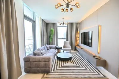 a living room with a couch and a tv at 1BR w Exclusive Lagoon Access in District One Meydan in Dubai