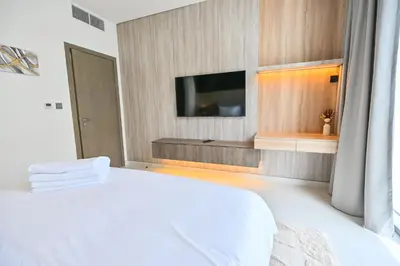 a bedroom with a white bed and a flat screen tv at Luxury and Spacious 1 Bedroom in District One Meydan in Dubai