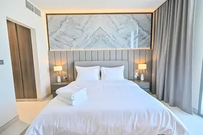 a bedroom with a large white bed with two pillows at 1BR Escape by the Lagoon in District One Meydan in Dubai