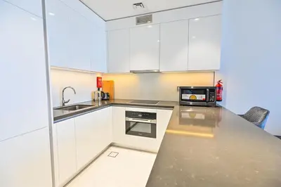 a kitchen with white cabinets and a sink and a microwave at Spacious 1BR with Burj Khalifa View in District One Meydan in Dubai