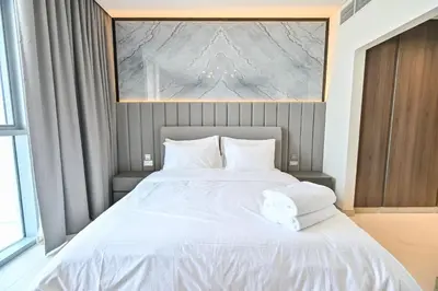 a bedroom with a large bed with white sheets and pillows at Spacious 1BR with Burj Khalifa View in District One Meydan in Dubai
