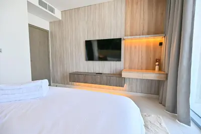 a bedroom with a white bed and a flat screen tv at Unique 1BR in District One Meydan in Dubai