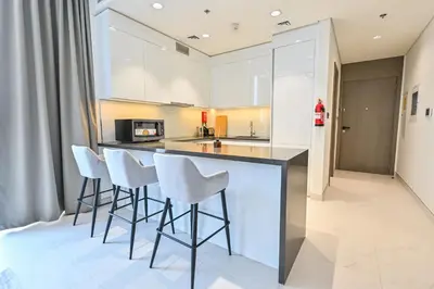 a kitchen with white stools and a counter top at Unique 1 Bedroom in District One Meydan in Dubai