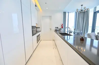 a kitchen with white cabinets and a black counter top at Unique 2 Bedroom in District One Meydan in Dubai