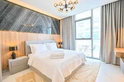 a bedroom with a white bed and a large window at 1BR Retreat by the Crystal Lagoon in District One Meydan in Dubai