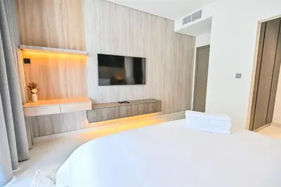 a bedroom with a white bed and a tv on a wall at 1BR Retreat by the Crystal Lagoon in District One Meydan in Dubai
