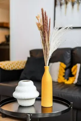 a table with a yellow vase and two bowls on it at Bright 1Bdr at Fortunato in Dubai