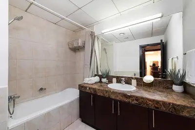 a bathroom with a sink and a bath tub and a mirror at Bright 1Bdr at Fortunato in Dubai