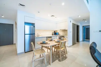 a kitchen and dining room with a table and chairs at Homes Beyond I 2 BR Apartment with Panoramic Creek View in Dubai