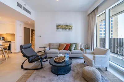 a living room with a couch and chairs and a table at Homes Beyond I 2 BR Apartment with Panoramic Creek View in Dubai