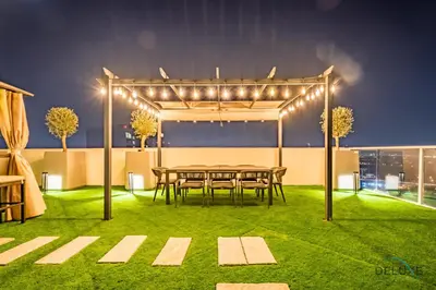 a patio with a table and lights on the grass at Spectacular 4BR Penthouse with Assistant Room in Hameni Tower, JVC by Deluxe Holiday Homes in Dubai