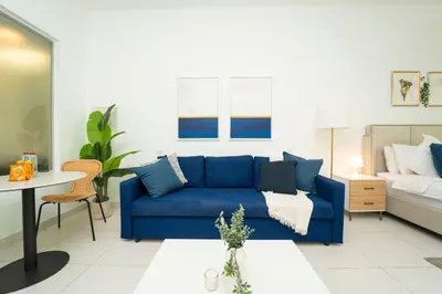 a living room with a blue couch and a bed at AWS Holiday Homes - Stylish Gem in the Palm in Dubai