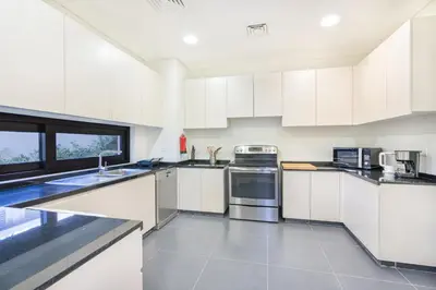 a white kitchen with white cabinets and appliances at Gorgeous 3BR Townhouse with Private Garden in Dubai