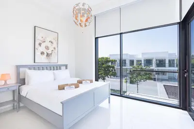 a white bedroom with a bed and a large window at Gorgeous 3BR Townhouse with Private Garden in Dubai