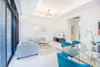 a living room with blue chairs and a glass table at Gorgeous 3BR Townhouse with Private Garden in Dubai