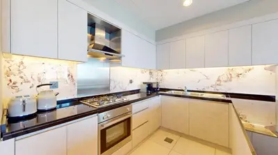 a kitchen with white cabinets and a stove top oven at The Signature - Two Bedroom in Downtown Dubai in Dubai