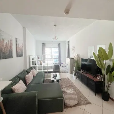 a living room with a green couch and a television at Fully Furnished Marina View - 1 Bedroom Apartment in Dubai