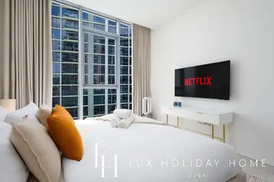 a bedroom with a bed and a tv and a window at LUX 2BR Lagoon View District One, 10 to 15 min Burj Khalifa in Dubai
