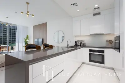 a kitchen with white cabinets and a large counter top at LUX 2BR Lagoon View District One, 10 to 15 min Burj Khalifa in Dubai