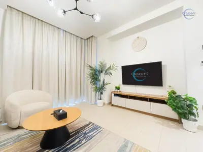 a living room with a tv and a table at Stylish 2BR Escape 2 Balconies Pool View in Dubai