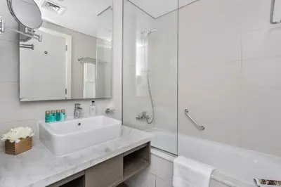 a white bathroom with a sink and a shower at Frank Porter - Damac Prive A in Dubai