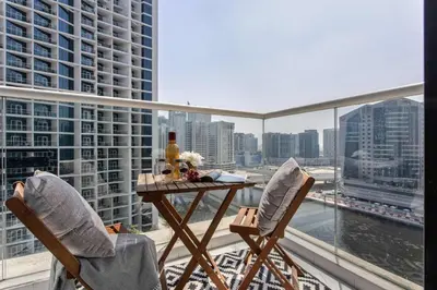 a table and chairs on a balcony with a view of a city at Frank Porter - Damac Prive A in Dubai