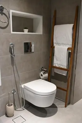 a bathroom with a toilet and a shelf with towels at 610 lagoon views in Dubai